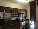 Galley kitchen features granite countertops, dark wood cabinetry, stainless appliances, and ample storage space at 3719 Conroy Rd # 2023, Orlando, FL 32839