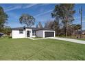 Newly built home with a white exterior, black accents, and a grassy lawn at 4411 Sw 132Nd Pl, Ocala, FL 34473