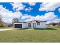 Single-story home with a two-car garage and landscaped lawn at 4690 Sw 139Th Place, Ocala, FL 34473
