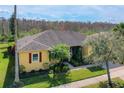 Aerial view of single story home with mature landscaping, a two car garage and view of wooded area at 127 Terra Vista Ln, Kissimmee, FL 34759