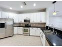 Bright kitchen featuring white cabinets, stainless steel appliances, and dark countertops at 1404 Lexington Avenue, Davenport, FL 33837