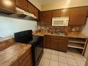 Condo kitchen with brown cabinets, tile counters, and appliances at 2024 Trinidad Ct, Kissimmee, FL 34741