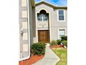 Front entrance with a brown door and landscaping at 2403 Melissa Ann Ct, Kissimmee, FL 34746
