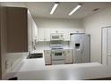 Efficient kitchen with white cabinetry, appliances, and a breakfast bar at 3133 Sun Lake Ct # B, Kissimmee, FL 34747