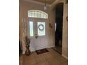 Inviting front door with decorative glass, transom window, and tiled entryway, creating a warm welcome at 6002 Renaissance Ct, St Cloud, FL 34772