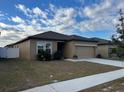 Tan house with a two-car garage and white fence at 1075 Aerides Way, Davenport, FL 33837