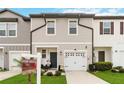 Two-story townhome with gray siding, white garage doors, and landscaping at 592 Madison Dr, Davenport, FL 33837