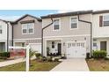 Two-story townhome with gray siding, white garage door, and landscaping at 592 Madison Dr, Davenport, FL 33837