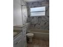 Clean bathroom with a bathtub, toilet, and marble tile at 1424 Sophie Way, Kissimmee, FL 34744