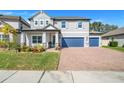 Two-story house with gray exterior, blue garage doors, and landscaped yard at 2230 Standing Rock Cir, Oakland, FL 34787