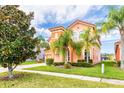 Two-story house with orange stucco and tile roof, showcasing a manicured lawn and palm trees at 4525 Stella St, Kissimmee, FL 34746