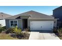 Exterior view of a single story house with a white garage door and landscaping at 522 Noble Ave, Davenport, FL 33837