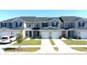 Well-maintained gray townhomes feature attached garages, green lawns, and matching shutters at 697 Stoney Point Cir, Davenport, FL 33896