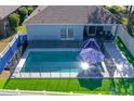 Aerial view of backyard with a fenced pool, artificial turf, and covered patio with lounge furniture at 9850 Hidden Dunes Ln, Orlando, FL 32832