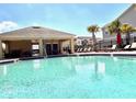 Sparkling community pool with lounge chairs and covered seating area under a bright blue sky at 2559 Sedge Grass Way, Orlando, FL 32824