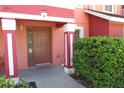 Inviting coral townhome entrance with a brown door and tidy landscaping at 261 Autumn Ln # 4, Kissimmee, FL 34743