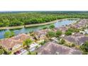 Aerial view of neighborhood townhomes with community pond surrounded by a lush tree line at 2833 Oakwater Dr # 169, Kissimmee, FL 34747