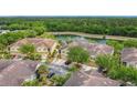 Aerial view of the townhomes with tile roofs overlooking a pond and surrounded by mature landscaping at 2833 Oakwater Dr # 169, Kissimmee, FL 34747