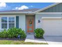 Close-up of home's entrance, showcasing the welcoming front door, sidelight window and well-kept landscaping at 401 Chayne Pl, St Cloud, FL 34771