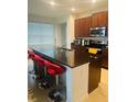 Kitchen with dark wood cabinets, stainless steel appliances, granite countertop and red barstools at 4033 Sunrise Ridge Blvd, Groveland, FL 34736