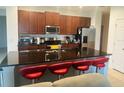 Kitchen featuring stainless appliances, dark wood cabinets, and seating area at 4033 Sunrise Ridge Blvd, Groveland, FL 34736