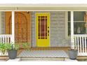 Welcoming front porch featuring a bright yellow door, decorative accents, and potted plants enhancing curb appeal at 723 New York Ave, St Cloud, FL 34769