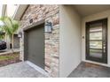 Modern front entrance with stonework, two-car garage, and a welcoming mat at 771 Drop Shot Dr, Davenport, FL 33896