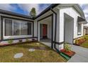 Inviting front entrance with decorative landscaping, a charming red door, and neutral-colored exterior at 83 Alameda Dr, Kissimmee, FL 34743