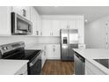 Bright kitchen with white cabinets, stainless steel appliances, quartz countertops, and wood flooring at 1503 August Gray Dr, Kissimmee, FL 34744