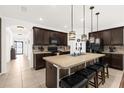 Spacious kitchen with island, dark cabinets, and stainless steel appliances at 3027 Serendipity Way, Davenport, FL 33896