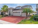 Two-story house with a gray exterior, red brick driveway, and palm trees at 3040 Cardillino Way, Kissimmee, FL 34741