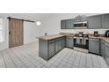 Modern kitchen features gray cabinets, stainless steel appliances, and a stylish barn door at 7933 Merrimac Cove Dr, Orlando, FL 32822