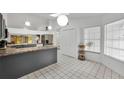 Bright kitchen with an island, modern lighting, white cabinets and tile floor at 7933 Merrimac Cove Dr, Orlando, FL 32822