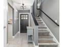 Welcoming entryway with modern gray walls, a stylish front door, and a staircase with a black handrail at 13008 Baltimore Woods Ln, Orlando, FL 32824