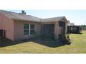 Exterior view of the home with a screened in lanai, windows, and well maintained yard at 156 Grand Canal Dr, Poinciana, FL 34759