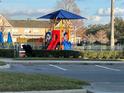 Community playground with a colorful play structure, shade canopy, and safety fencing at 4010 San Gallo Dr # 105, Kissimmee, FL 34741