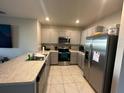 Well-lit kitchen with gray cabinets, stainless steel appliances, and a tile floor at 735 Chinoy Rd, Davenport, FL 33837