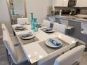 Elegant dining area features a modern white table set for six, adjacent to the open kitchen at 8885 Cabot Cliffs Dr # 103, Davenport, FL 33896