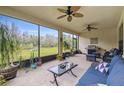 Screened-in patio with ceiling fans, comfortable seating, BBQ, various plants and view to the backyard at 1398 Del Mar Dr, Kissimmee, FL 34759