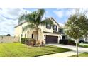 Two-story home featuring a two-car garage, manicured lawn, and mature trees at 3199 Turret Dr, Kissimmee, FL 34743