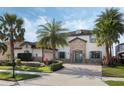 Charming two-story home with a stone facade, mature palm trees, and a paver driveway at 4959 Tennessee Lake Dr, Auburndale, FL 33823
