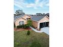 Aerial view of peach house with palm tree, shrubbery, lawn, driveway, roof, and screen door garage at 5674 Sycamore Canyon Dr, Kissimmee, FL 34758