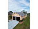 Angle view of peach house with lawn, shrubbery, roof, long driveway, and screen door garage at 5674 Sycamore Canyon Dr, Kissimmee, FL 34758