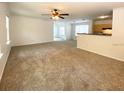 Spacious living room featuring neutral carpet, ceiling fan, and a pass-through to the kitchen area at 1017 Siena Park E Blvd, Celebration, FL 34747