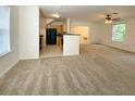 Open living space with view of kitchen, featuring neutral carpet and ample natural light from multiple windows at 1017 Siena Park E Blvd, Celebration, FL 34747