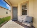 Cozy front porch with stone accents, a comfortable chair, and a view of the well-maintained landscape at 1036 Salamanca Pl, Davenport, FL 33837