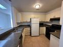 Well-lit kitchen features tile floors, white appliances, dark countertops and plenty of cabinets at 1324 Eagle Ln, Winter Garden, FL 34787