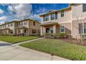 Inviting townhomes with well-maintained lawns and neutral exteriors under a partly cloudy blue sky at 1567 Dawnview Way, Kissimmee, FL 34744