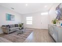 A cozy living room featuring a gray sofa, glass table, tile floors, and bright natural light at 1732 Pacific Rd, Kissimmee, FL 34759