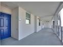 A bright, airy hallway leading to a unit's blue front door with contemporary white walls and metal railings at 3180 Paradoux Circle # 205, Kissimmee, FL 34746